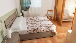 Ein ordentlich eingerichtetes Schlafzimmer mit Bett, Nachttisch, Lampe, Stuhl und Kleiderschrank.