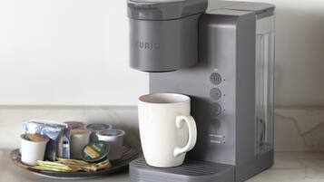 Una cafetera Keurig con una taza blanca y cápsulas de café sobre una encimera de cocina.