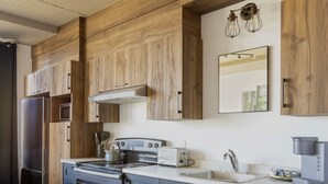 Une cuisine moderne dotée de meubles en bois, d’appareils électroménagers en acier inoxydable et d’un four encastré.