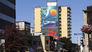 Un edificio con un gran mural que representa un paisaje con sol, luna y olas.
