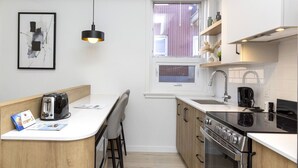 A compact kitchen with a central island, a built-in oven, a stovetop, and a window above the sink.