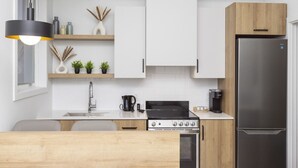 A modern kitchen with white cabinets, a stainless steel refrigerator, a gas stove, and a wooden island.