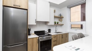 Eine moderne Küche mit einem Edelstahl-Kühlschrank, einem schwarzen Herd und Holzschränken.
