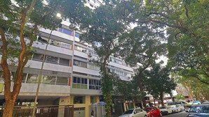 A multi-story building with balconies, parked cars, and trees. - C061 (Rio de Janeiro)