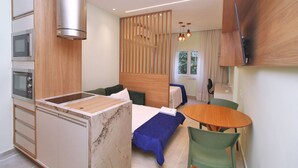 A modern hotel room with a kitchenette, a bed, a dining table, and a view of the outdoors. - C061 (Rio de Janeiro)