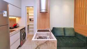 A compact kitchen with a built-in washing machine, a sink, and a green sofa in the adjacent living area. - C061 (Rio de Janeiro)