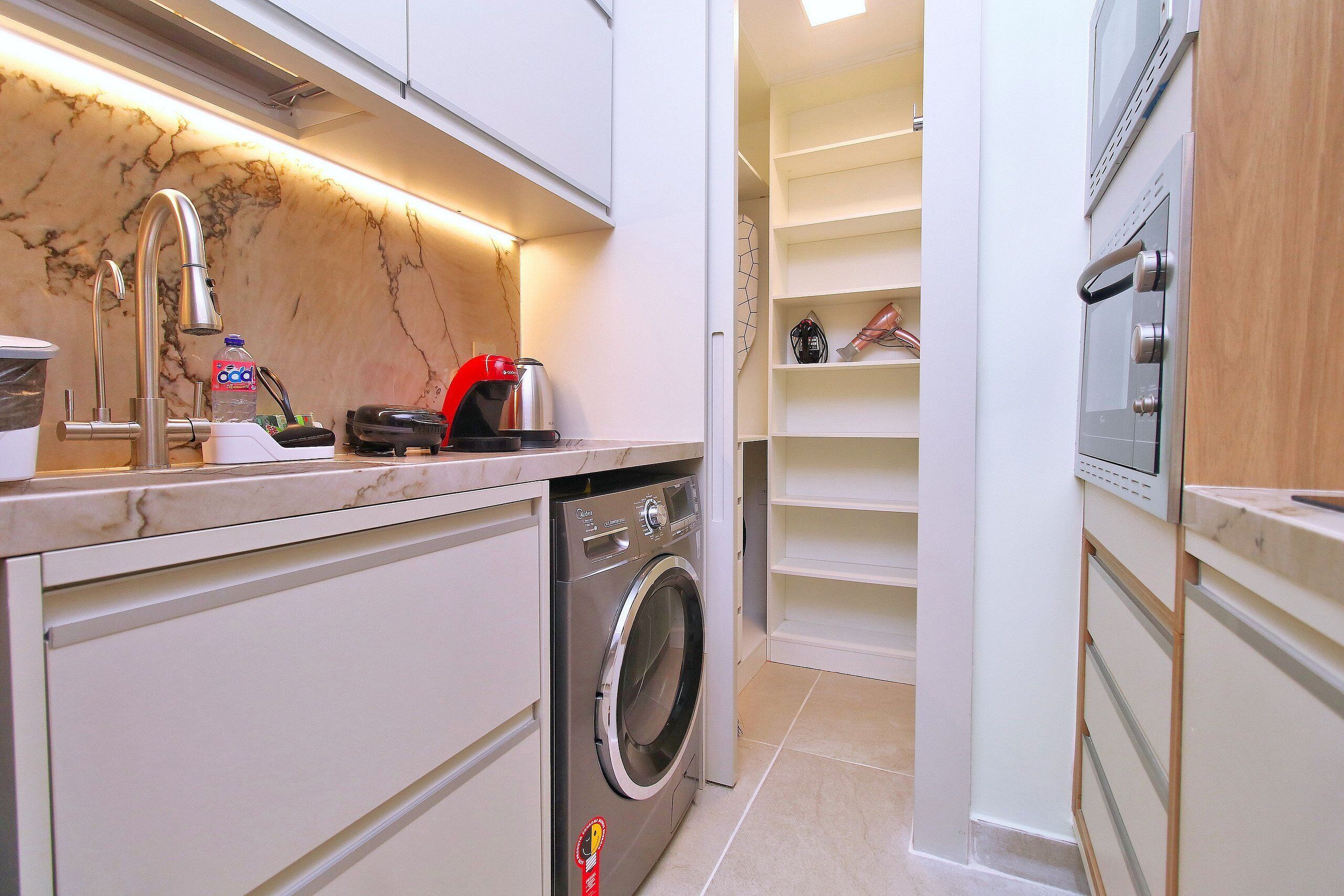 A compact kitchen with a built-in washing machine, a microwave, and a coffee maker.