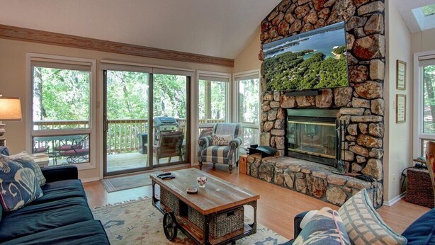 A spacious living room with a stone fireplace, large windows, and a cozy seating area.
