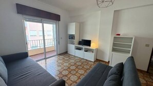 Una sala de estar con sofá, televisión y balcón.