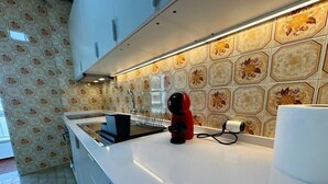 Una cocina moderna con encimera blanca, hervidor eléctrico rojo y salpicadero decorado.
