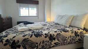 Un dormitorio con cama, cómoda, ventana con persianas y lámpara de noche.