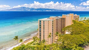 A beachfront hotel with multiple high-rise buildings, a clear view of the ocean, and lush greenery. - Kaanapali Ocean Front 1 Bedroom! Mahana 617! (Lahaina)