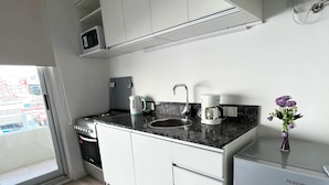 Eine moderne Küche mit weißen Schränken, einer Granit Arbeitsplatte, einer eingebauten Mikrowelle, einer Kaffeemaschine und einem Kühlschrank.
