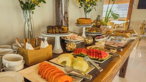 A buffet with various dishes and fruits, including watermelon and carrots, arranged on a long table. - Pousada Recanto Dourado (Bonito)