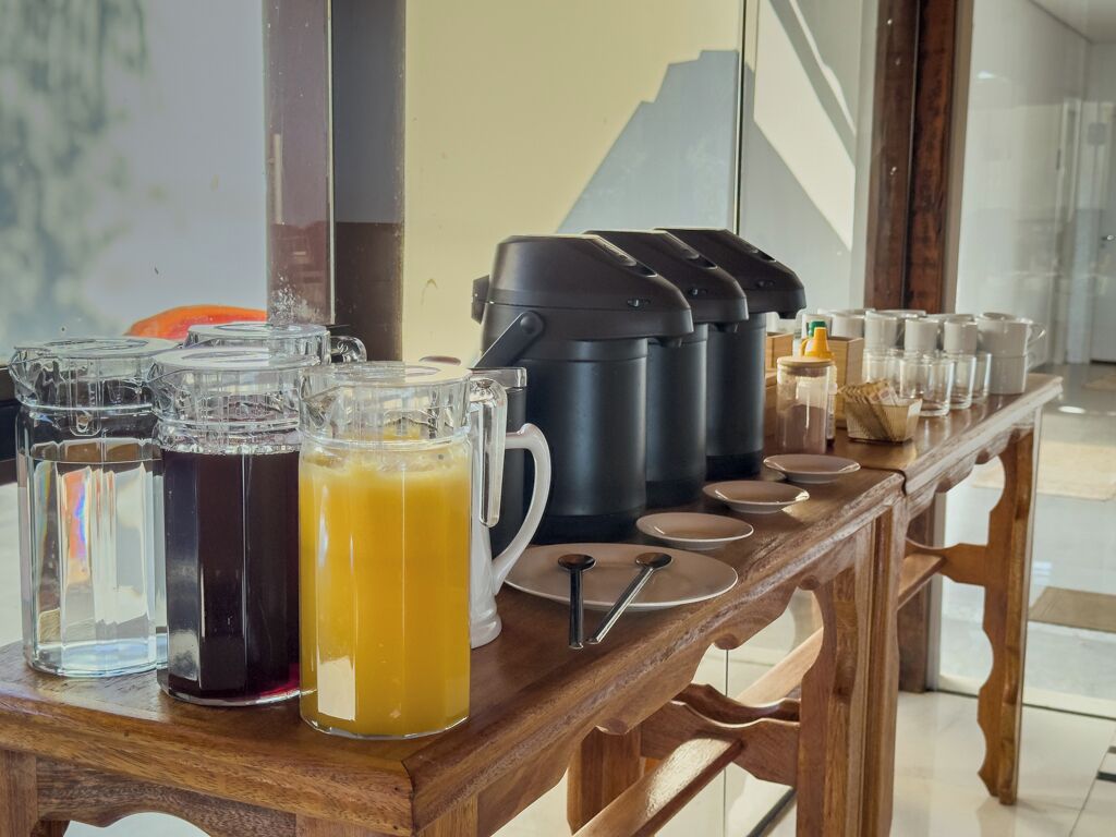 A breakfast buffet setup with various beverages and a coffee maker on a wooden table.