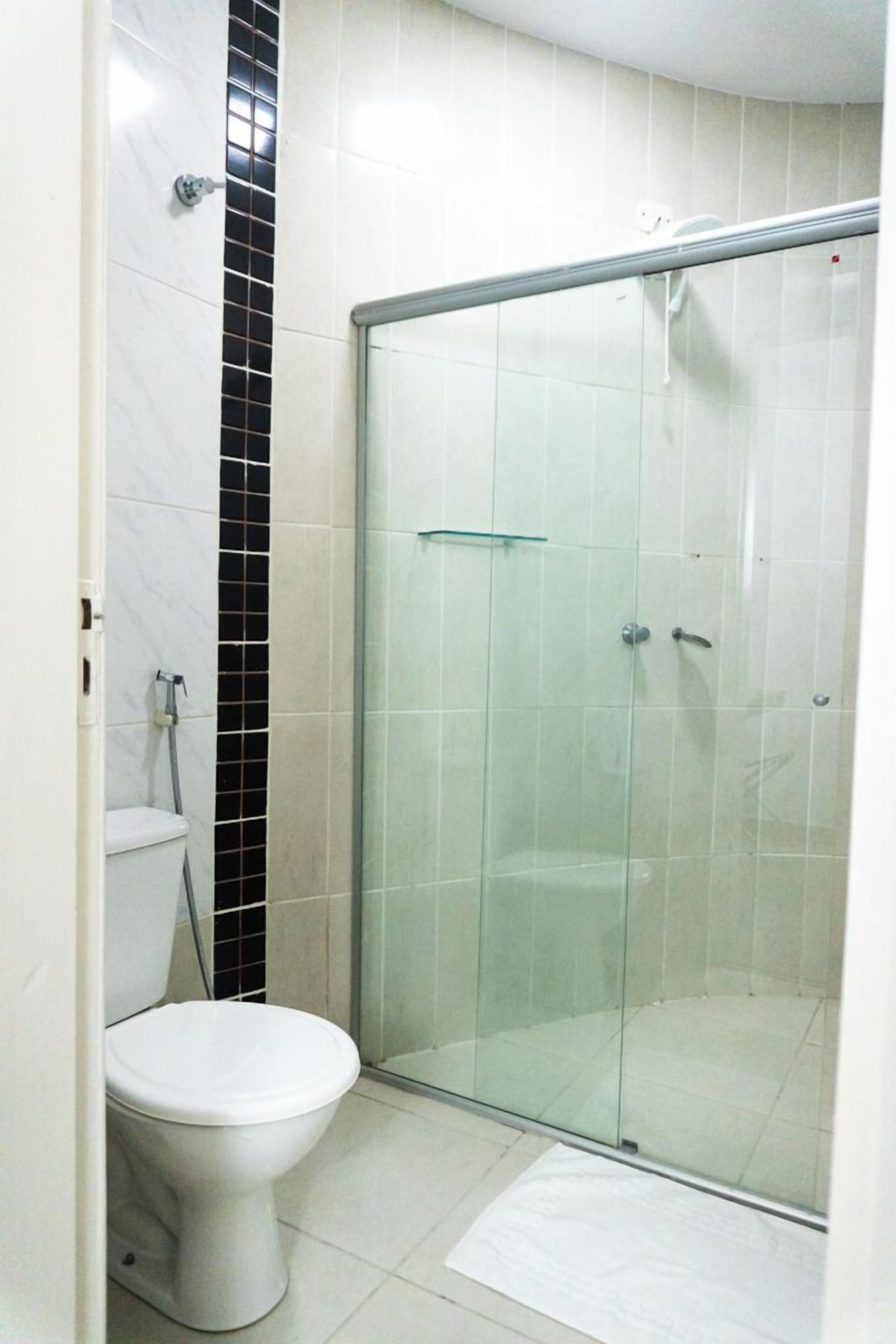 A bathroom with a toilet, a glass shower enclosure, and a tiled floor.