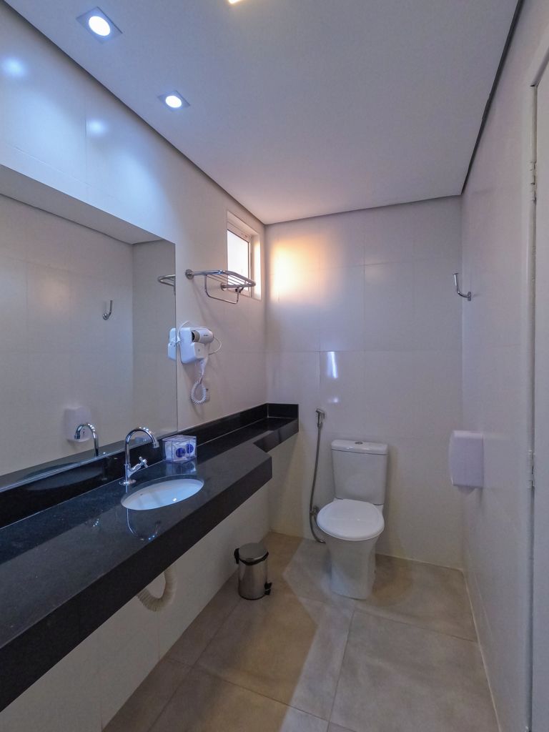 A modern bathroom with a black countertop, a sink, a toilet, and a shower.