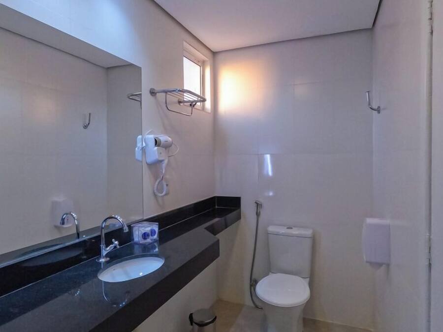 A modern bathroom with a black countertop, a sink, a toilet, and a shower.