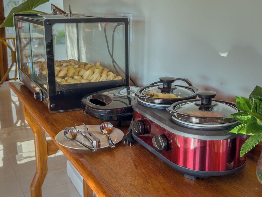 A buffet setup with a glass display case containing pastries and a red electric stove with pots.