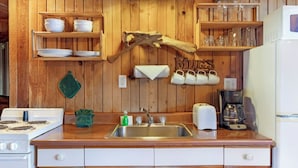 Une cuisine avec des murs en bois, un évier, une cuisinière et une machine à café.