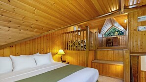 A wooden cabin bedroom with a bed, a nightstand, a lamp, and a window with a view of greenery. - 2BR Ocean View Cabin - 1 min walk to world class beach! (Eastsound)