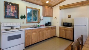 Una cocina con armarios de madera, estufa, fregadero y refrigerador.