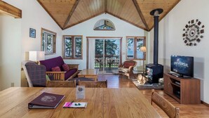 Un salón acogedor con techo de madera, chimenea y televisor.