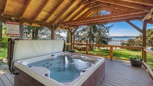 Een houten terras met een jacuzzi, een bord met spa-regels en uitzicht op de oceaan.