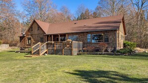 A wooden cabin with a porch, a staircase, and a fenced yard. - 3BR Ocean View Farmhouse - 1 min walk to prime west-facing beach! (Eastsound)