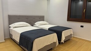 A bedroom with two beds, a window, and an air conditioning unit. - Charming 2-bedroom apartment with WiFi, AC in fabulous Tiranë (Tiranë)