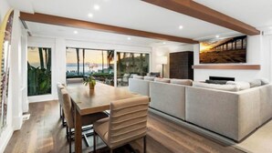 A modern living room with a large window, a dining area, and a sofa set.