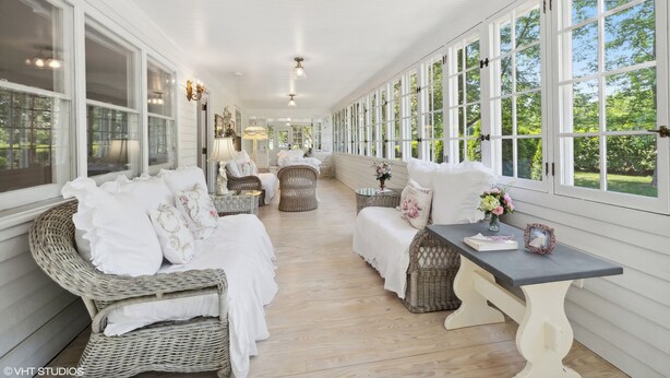 A covered porch with wicker furniture, a bench, and a table with a vase of flowers. - Newly renovated, 7700 Sq. Ft,  8BR, 7BTH, Heated Pool, Hot Tub, Arcade Game Barn (Sawyer)
