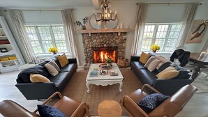 A cozy living room with a stone fireplace, leather sofas, and a coffee table. - Newly renovated, 7700 Sq. Ft,  8BR, 7BTH, Heated Pool, Hot Tub, Arcade Game Barn (Sawyer)
