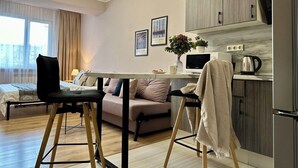 Un salon moderne comprenant un canapé, une table à manger et un coin cuisine équipé d’un four à micro-ondes et d’une bouilloire.