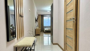 Un couloir avec un banc, des portes en bois et un lit à l’arrière-plan.