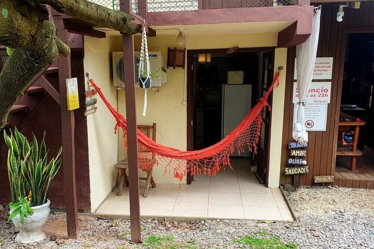 Un petit bâtiment avec un hamac, une plante en pot et un panneau indiquant une durée de séjour de 22 heures.