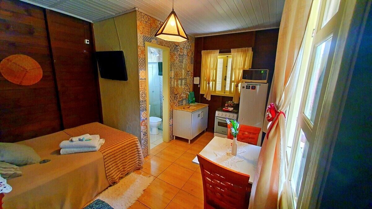 Habitación compacta con cama, kitchenette pequeña y baño.