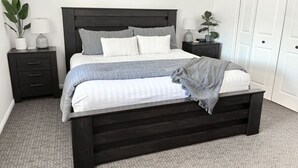 A bedroom with a dark wooden bed, white bedding, and a grey carpet. - Massive Backyard with Private Pool and Spa (Hurricane)