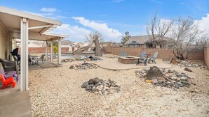 An outdoor patio with a covered seating area, a fire pit, and a pool. - Massive Backyard with Private Pool and Spa (Hurricane)
