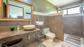 Une salle de bain moderne avec un grand miroir, un lavabo, des toilettes et un espace douche.