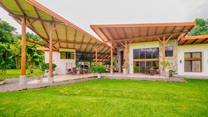 Un espace extérieur abrité, doté d’une terrasse, de sièges et d’un bâtiment avec de grandes fenêtres.
