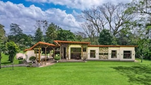 Une maison à deux étages dotée d’un patio couvert, d’un garage et d’une pelouse bien entretenue.