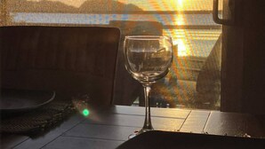 A table with a wine glass and a plate, set against a view of a sunset over water. - 2BD Beachfront Condo @ Playa Potrero (Provincia de Guanacaste)