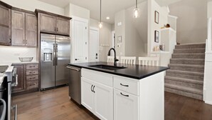 Una cocina moderna con armarios blancos, un refrigerador de acero inoxidable y una isla de encimera negra.