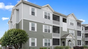 A multi-story apartment building with a green exterior and white trim.