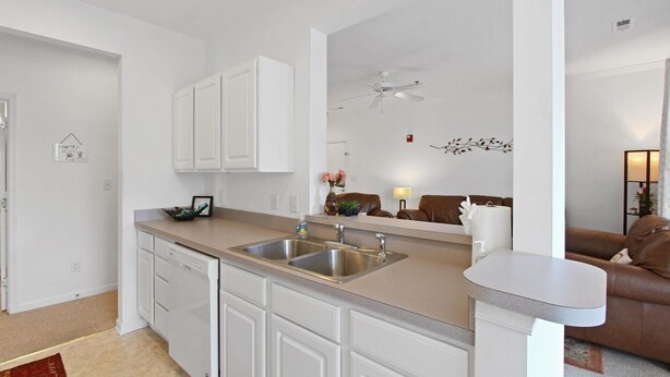 A modern kitchen with white cabinetry, a double sink, and a countertop.