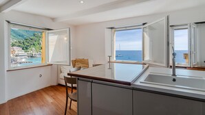 Eine moderne Küche mit großen Fenstern und Blick auf eine Küstenstadt und das Meer.