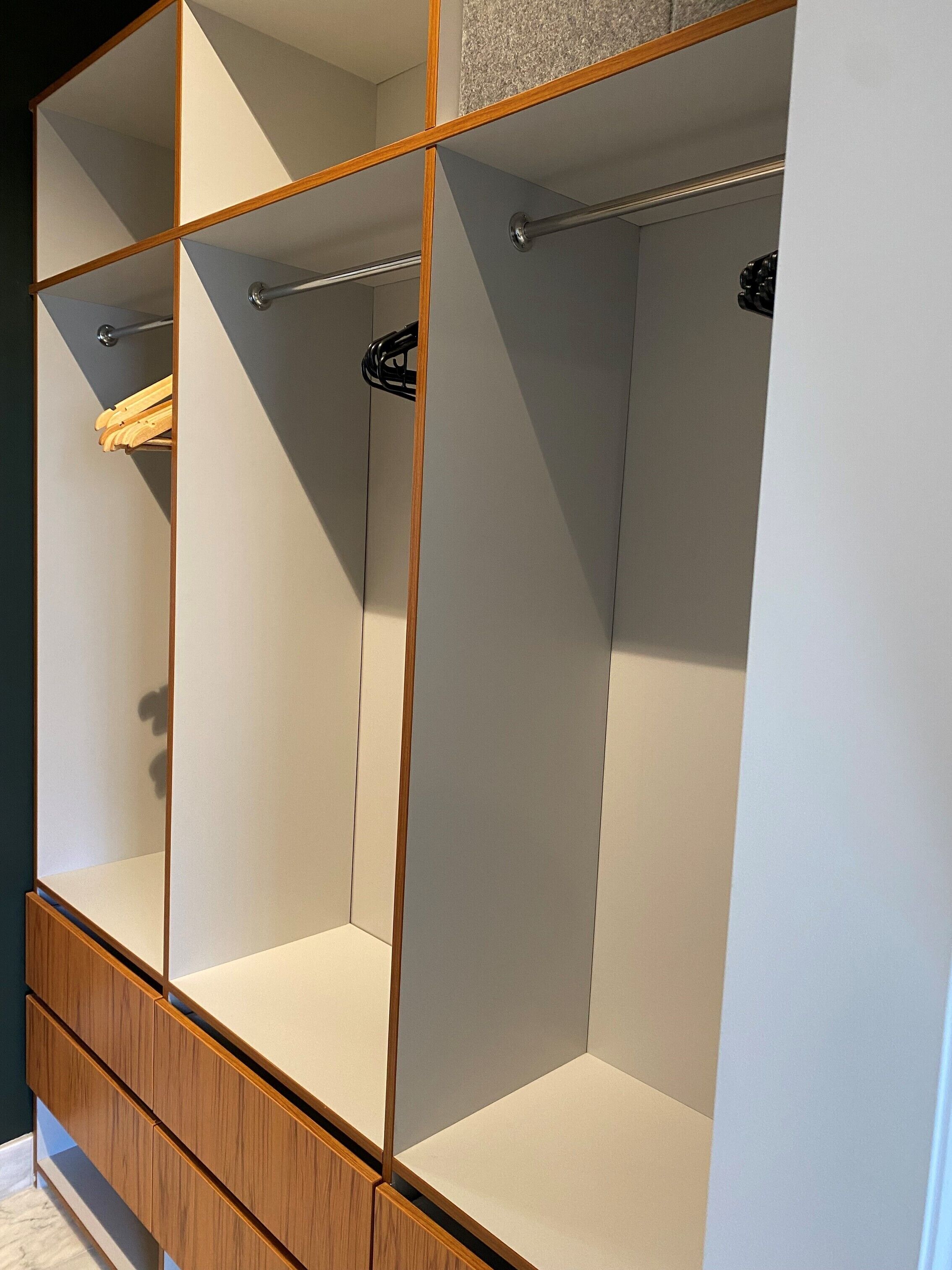 A walk-in closet with open shelving, a hanging rod, and a wooden base.