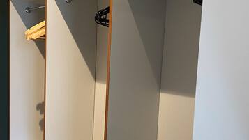 A walk-in closet with open shelving, a hanging rod, and a wooden base.