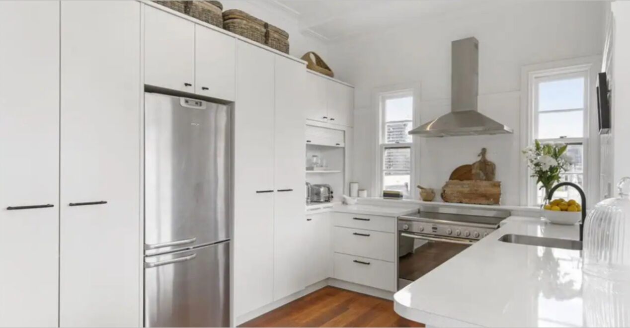 A modern kitchen with white cabinetry, stainless steel appliances, and a central island.